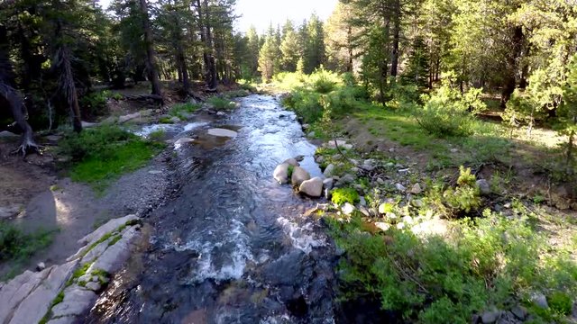 Highland Lakes Creek Arnold California Mountain rocky stream in the sun 4k aerial tracking foward