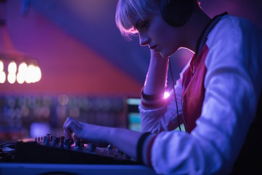 Female DJ listening to headphone while playing music