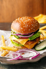 Tasty hamburger with french fries on a wooden board