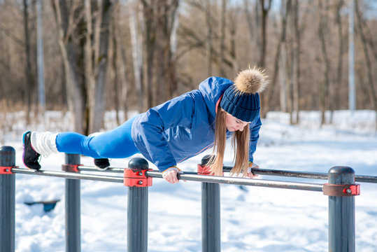 Beautiful young girl doing stretching, fitness on a sports field in winter against a background of deciduous forest. Winter sports concept photo