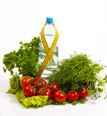 Concept of healthy active lifestyle and diet control. Red  tomatoes, parsley, cilantro, dill,, lettuce. Bottle with pure drinking water and yellow measuring tape. White background.
