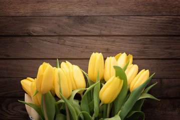 Naklejka premium Fresh yellow tulips on rustic wooden table