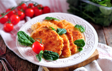 Schnitzel from chicken breast with green salad, rustic style.