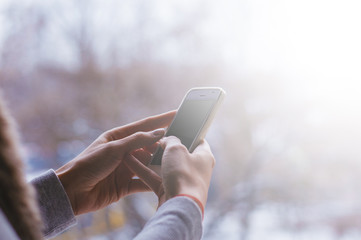 Closeup of female hands using cellphone outdoor, writing a message