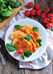 Schnitzel from chicken breast with green salad, rustic style.