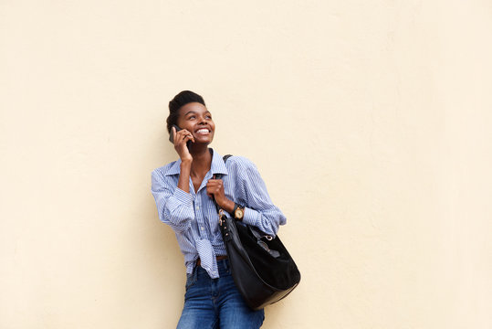 Smiling African American Woman Against Wall With Cellphone