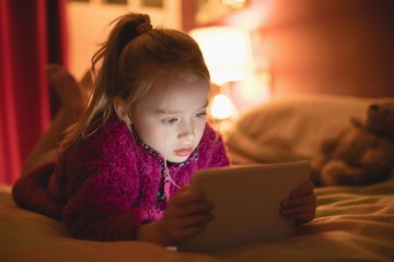 Girl sitting using digital tablet in bedroom
