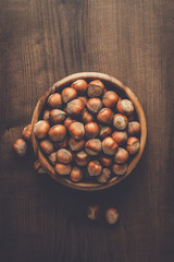 hazelnuts in wooden bowl on the brown table background