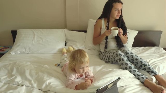 Woman and baby girl watching cartoons on tablet computer