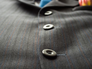 Black buttons on a man's suit background with blue tie., close up