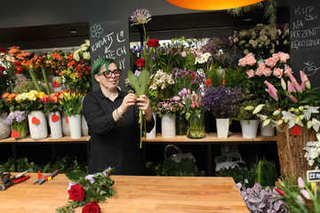 Kobieta w kwiaciarni robi bukiety z kwiatów ciętych. - obrazy, fototapety, plakaty