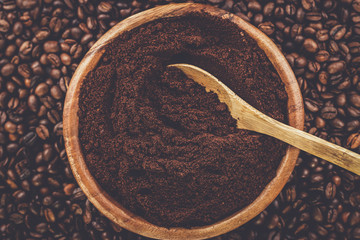 coffee beans and wooden bowl full of ground coffee on the table background