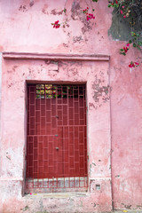 A colorful pink door with flowers in the Getsemani neighborhood in Cartagena, Colombia.