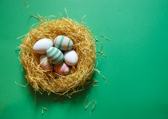 Colorful vintage easter eggs in nest on green background