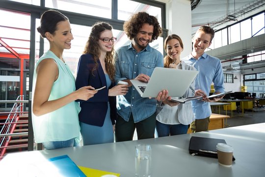 Smiling business team discussing over laptop in meeting