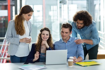 Smiling business team discussing over laptop in meeting