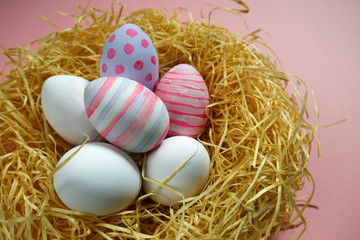 Colorful vintage easter eggs in nest on pink background