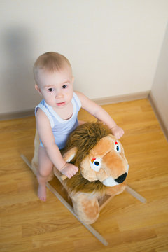 Cute small baby boy riding on the lion toy . Happy child emotions.