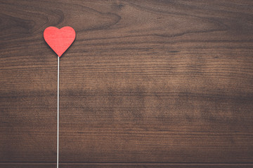 red heart shape on stick over wooden background