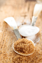 Brown sugar in spoon on rustic wooden table.