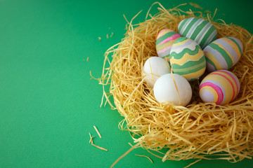Naklejka na ściany i meble Colorful vintage easter eggs in nest on green background
