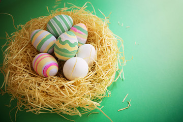 Colorful vintage easter eggs in nest on green background