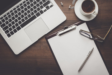 view from above. brown wooden office table with cup of coffee, notepad and laptop computer