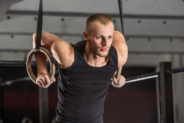 Fototapeta na wymiar Fitness Man Training Arms With Gymnastics Rings