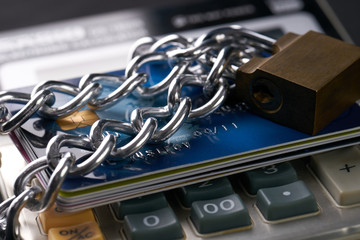 Close up of Chained with padlock credit and debit bank cards on calculator - credit card data encryption protection concept.
