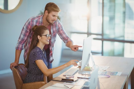 Graphic designers discussing over personal computer