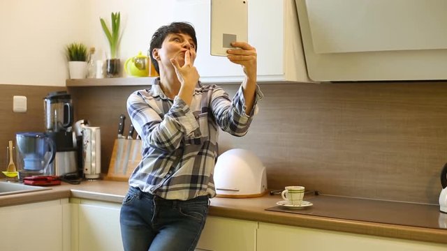 Attractive woman having fun while doing selfies on tablet in the kitchen
