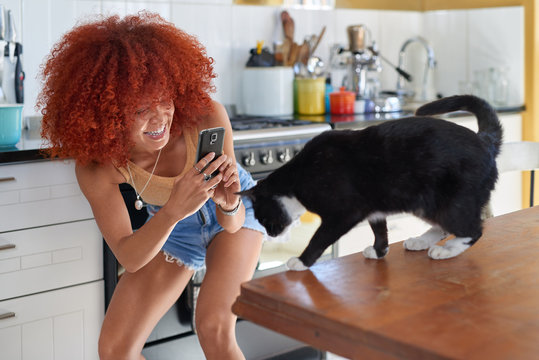 Smiling woman trying to take a photo of her pet cat