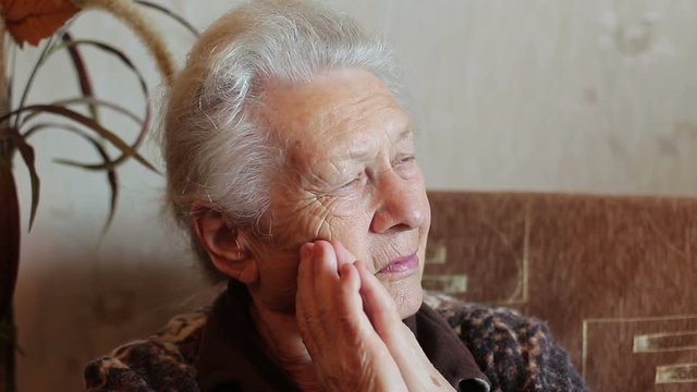 Sad old woman sitting in an armchair and thinking. Close up