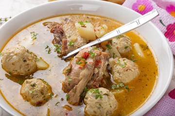Soup with meatballs and chicken meat in bowl