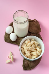 Ingredients - eggs, milk and crackers on a pink background. From above. Vertical.