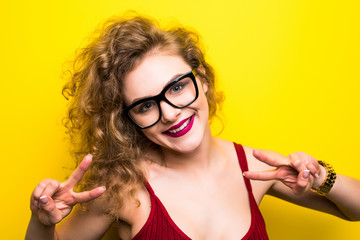 Pretty woman doing victory gesture over yellow backgound