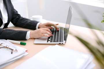 Close up of business woman  hands  typing on  laptop computer in the white colored office.