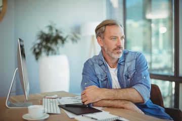 Thoughtful graphic designer sitting at desk