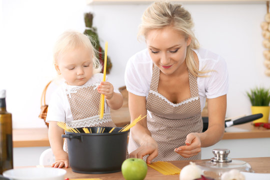 Happy family in the kitchen. Mother and child daughter cooking pasta