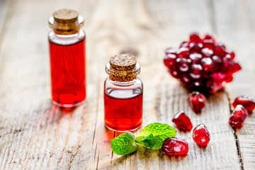 sliced pomegranate and extract in glass on wooden background