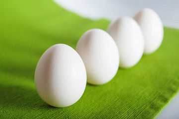 White eggs on a green fabric texture background