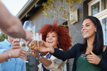 Attractive mixed race people cheers at party, friends having a toast wine glasses cocktails 