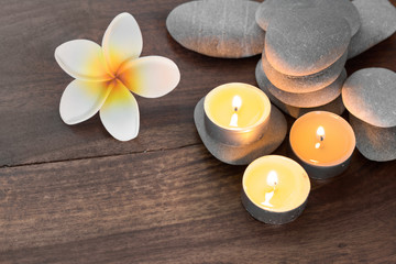 spa composition with candles pebble stones and flowers on wooden table
