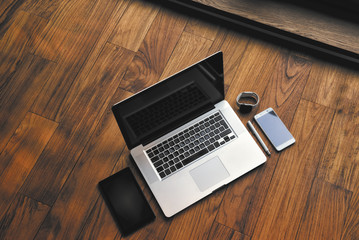 Office stuff with notepad, laptop, smartphone, pen and watch on the brown wooden desk. Top view with copy space.