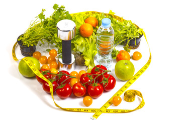 Concept of healthy active lifestyle and diet control. Red and yellow tomatoes,parsley, apples,mandarins,lettuce. Fitness dumbbell and bottle with water.Fruits and greens in circle of measuring tape.