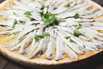 Close-up of anchovies with olive oil and vinegar on wooden plate. Healthy food.
