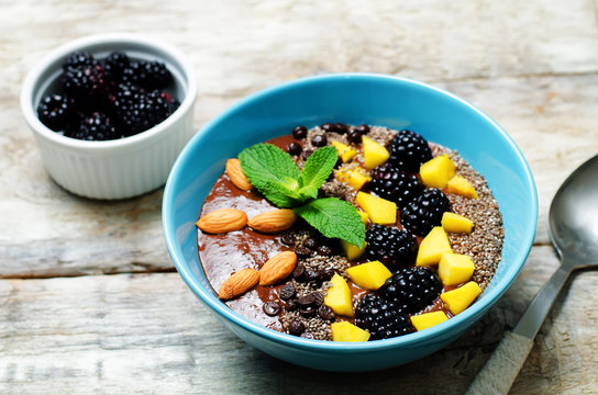 Chocolate smoothies breakfast bowl with chocolate chips, mango, blackberry, almond and Chia seeds