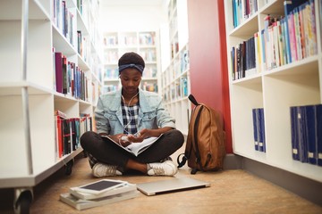 Fototapeta na wymiar Schoolgirl listening music on headphones in library