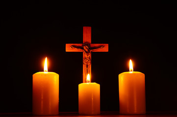 Crucifix and three burning candles in the darkness. Pray to Jesus Christ. 3