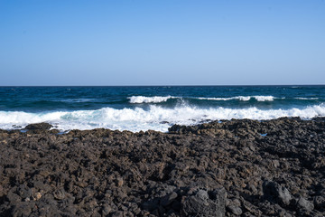 Fototapeta na wymiar Black volcano stones on the coastline of the Atlantic Ocean in Canarias 